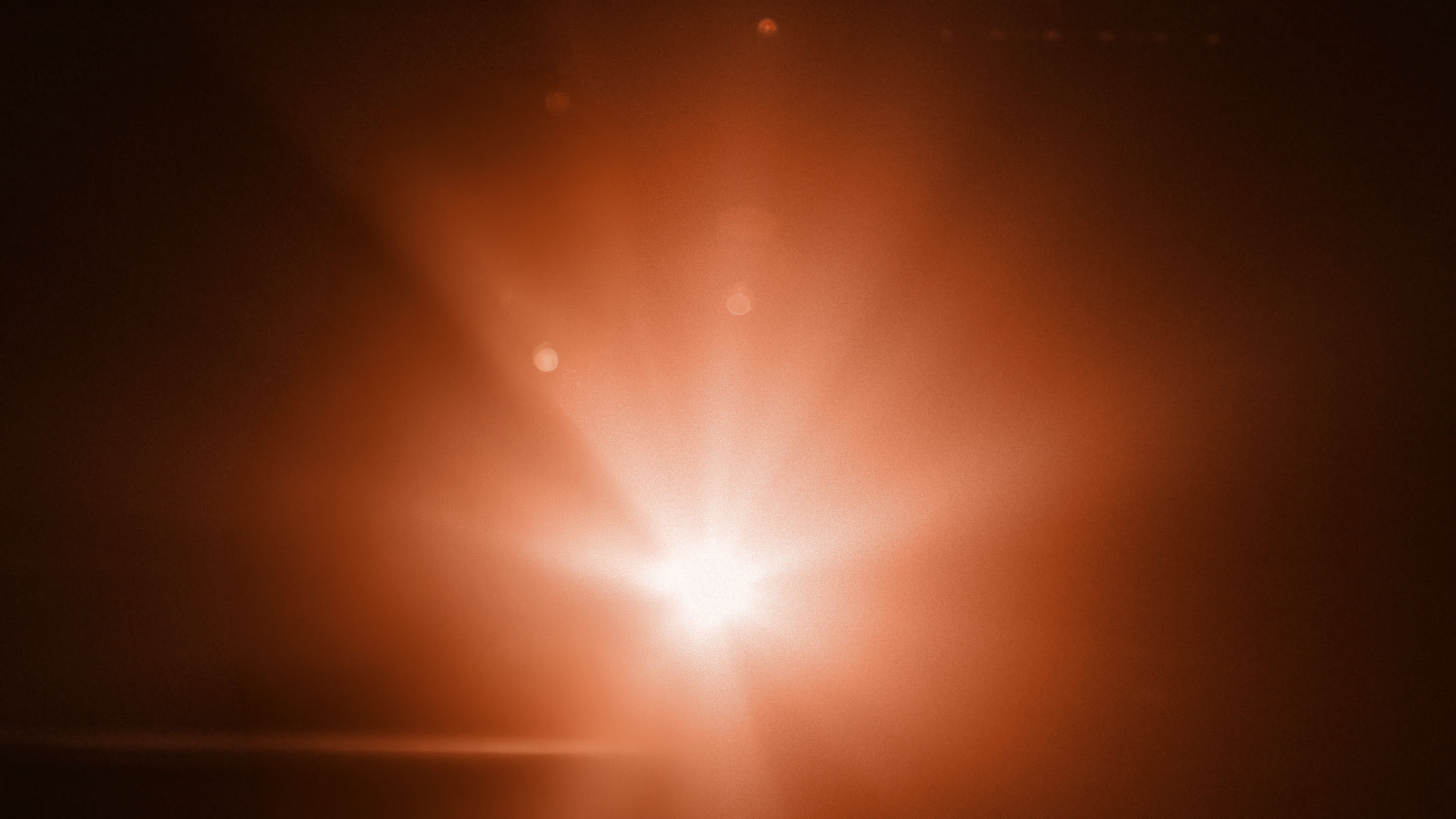 Burst of warm orange stage light cutting through haze, a press-conference glare