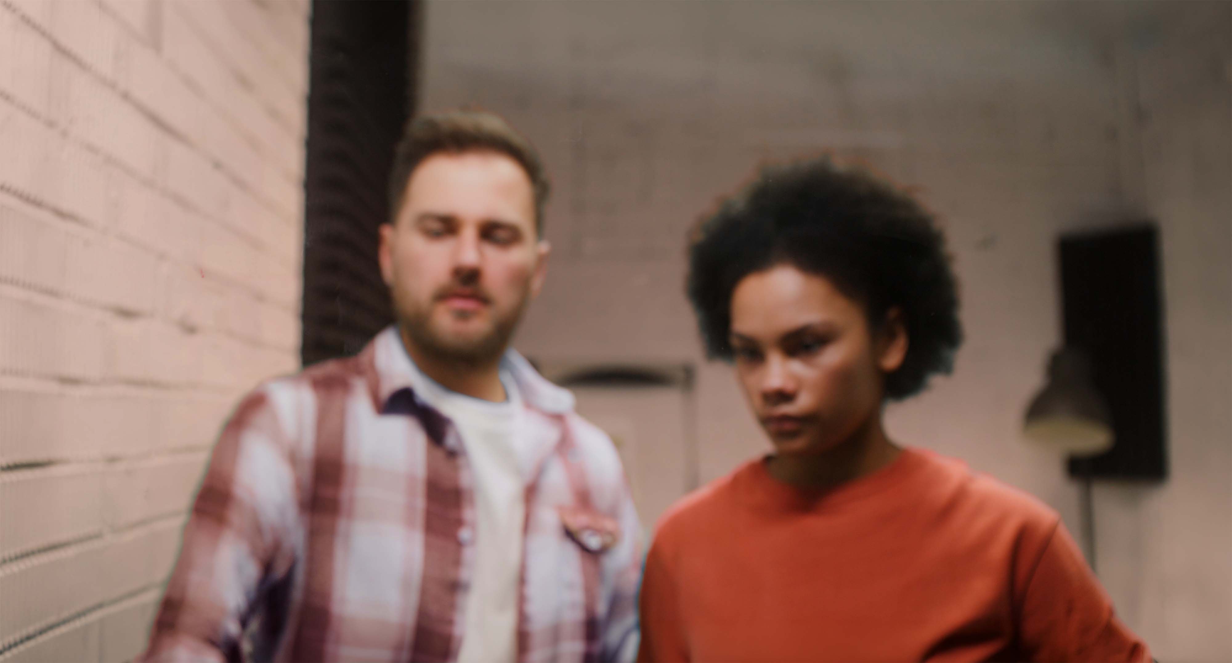 Two people in a workshop space looking down at something together, deep in discussion